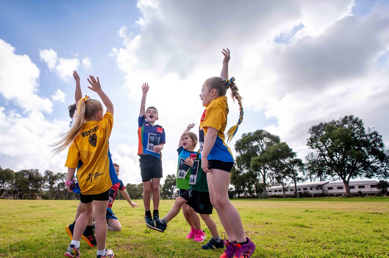 Young players leaping and cheering with their arms up at a sports carnival